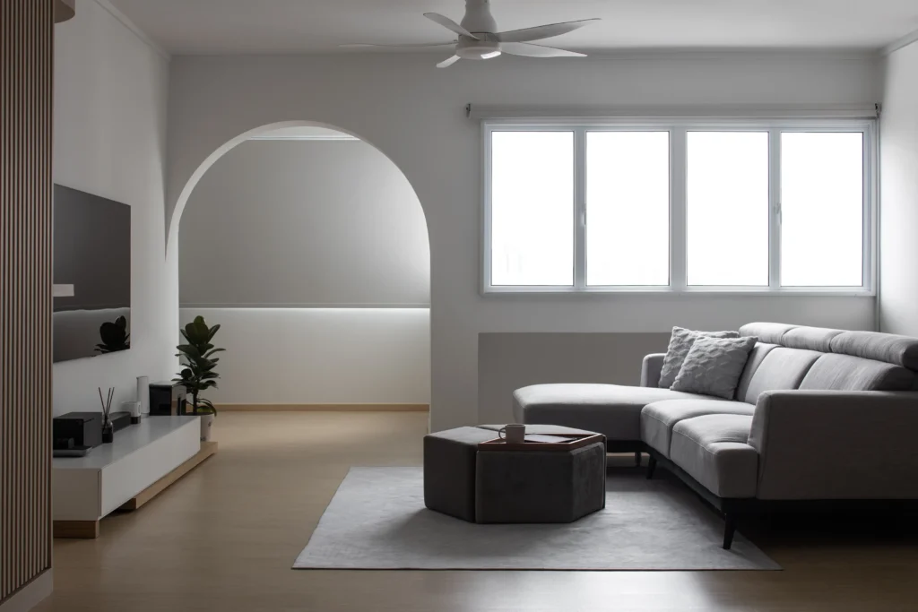 Minimalist 4-room HDB living room with archway, grey sofa and large windows in Singapore