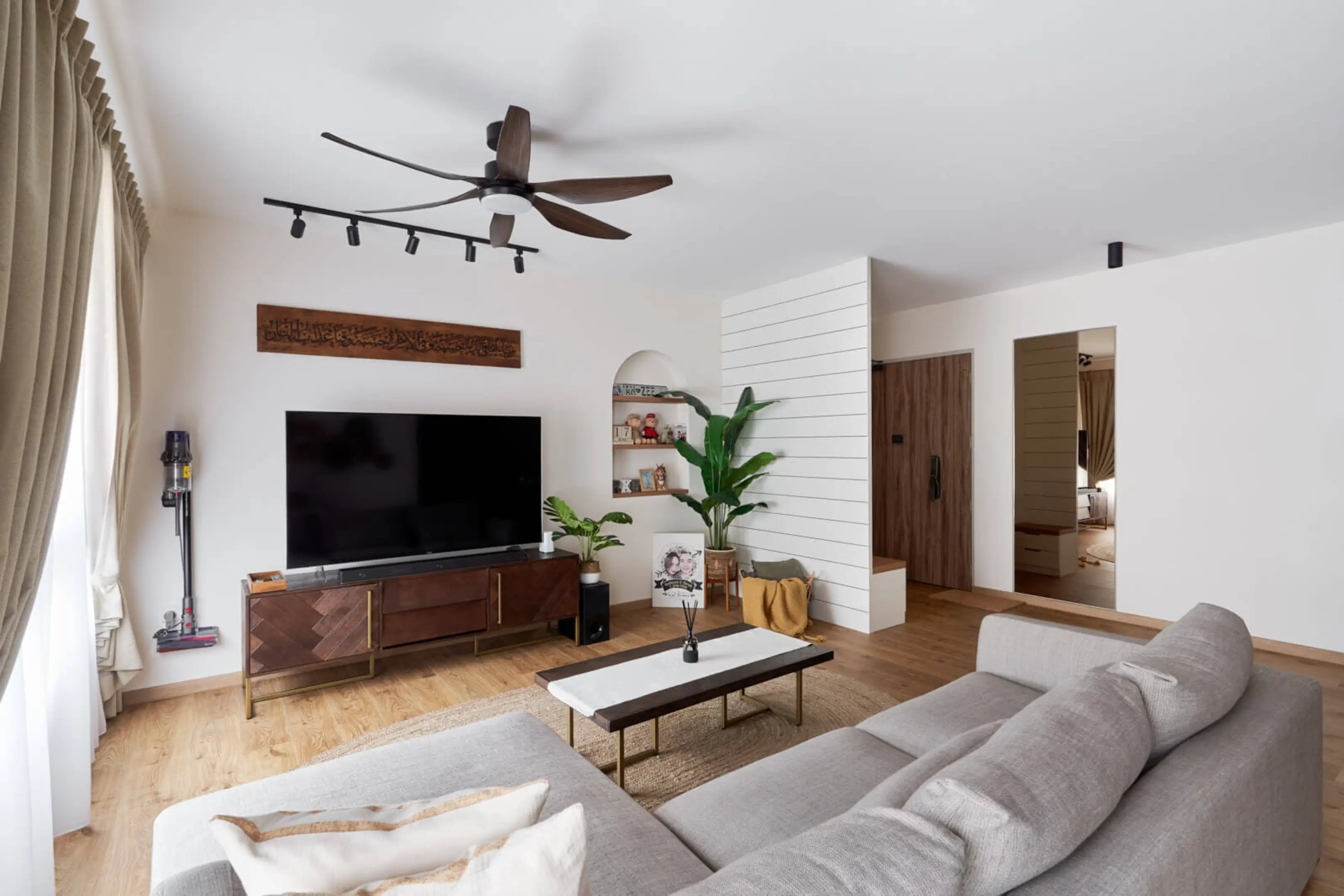 Cosy 4-room HDB living room with wood TV console, track lights and L-shaped sofa