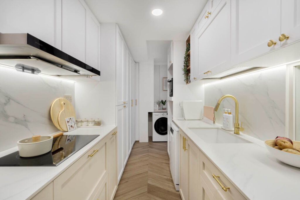 Small kitchen design galley layout in white with marble backsplash, gold hardware, induction hob and herringbone floor