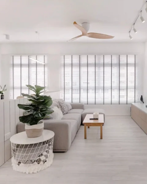 Minimalist interior design living room in Singapore HDB with grey sectional sofa, white walls and full-height blinds.