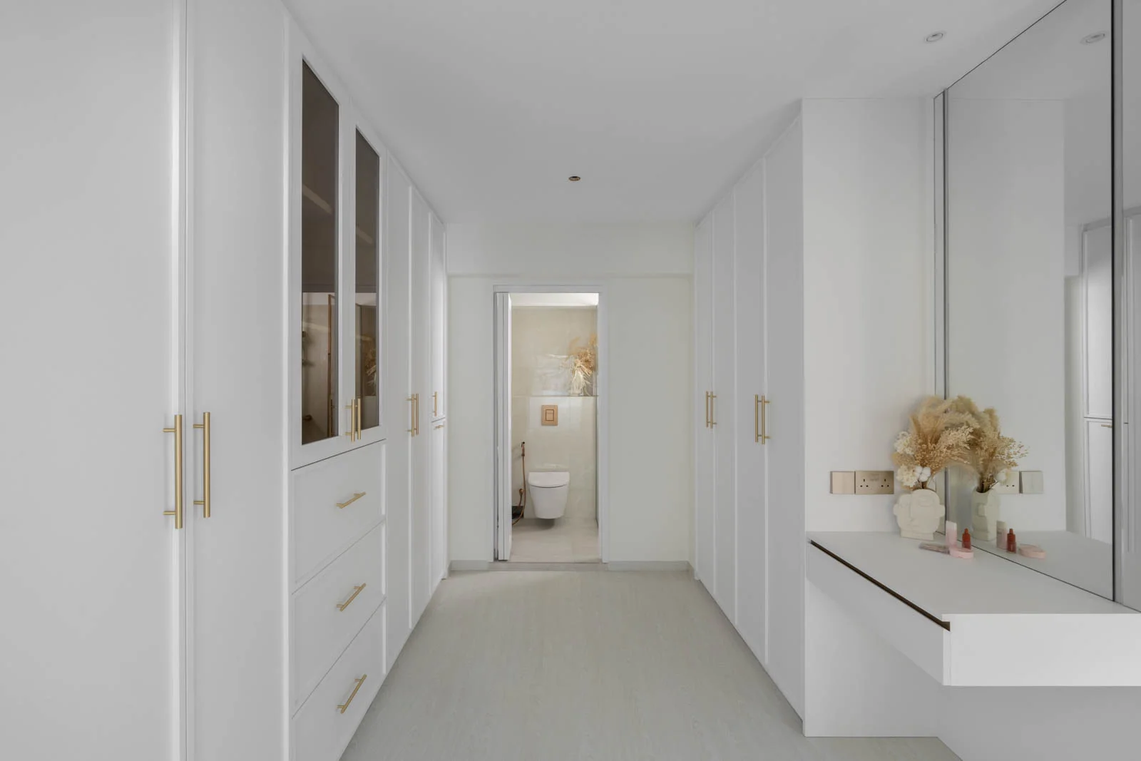 Bright walk-in wardrobe in resale HDB flat, gold handles and neutral palette controlled by smart switches