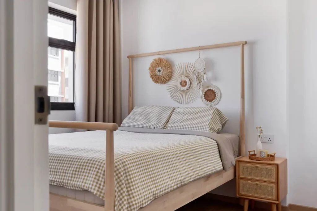 Scandinavian bedroom with light wood bed, neutral gingham bedding, rattan nightstand, soft curtains and bright natural light.