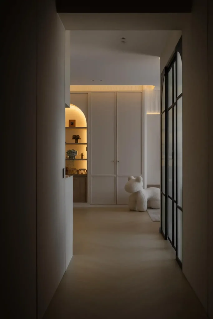 Warm ambient hallway with backlit arch shelves and a plush sculpture, showing layered architectural lighting.