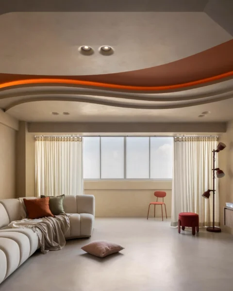 Lounge view through an archway, featuring a curved ceiling with cove lighting, a cream sofa, and a wall-mounted TV.