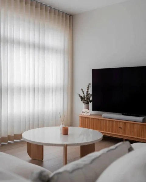 Soft minimalist living room with ripple-fold sheer curtains, round white coffee table and fluted TV console
