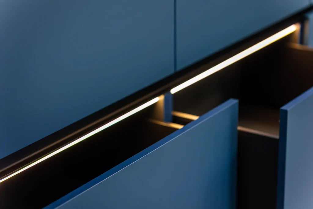 Adhesive LED light strip under cabinet illuminating drawers—a removable, renter-friendly upgrade.