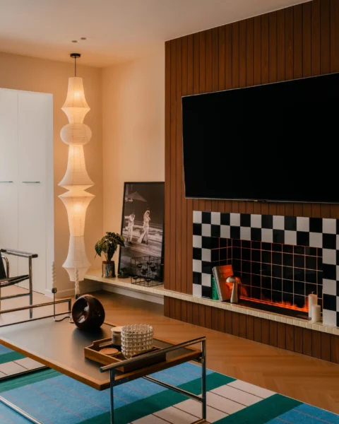 Retro-inspired TV wall with vertical wood paneling, checkerboard tiles, and a fireplace-style feature niche.