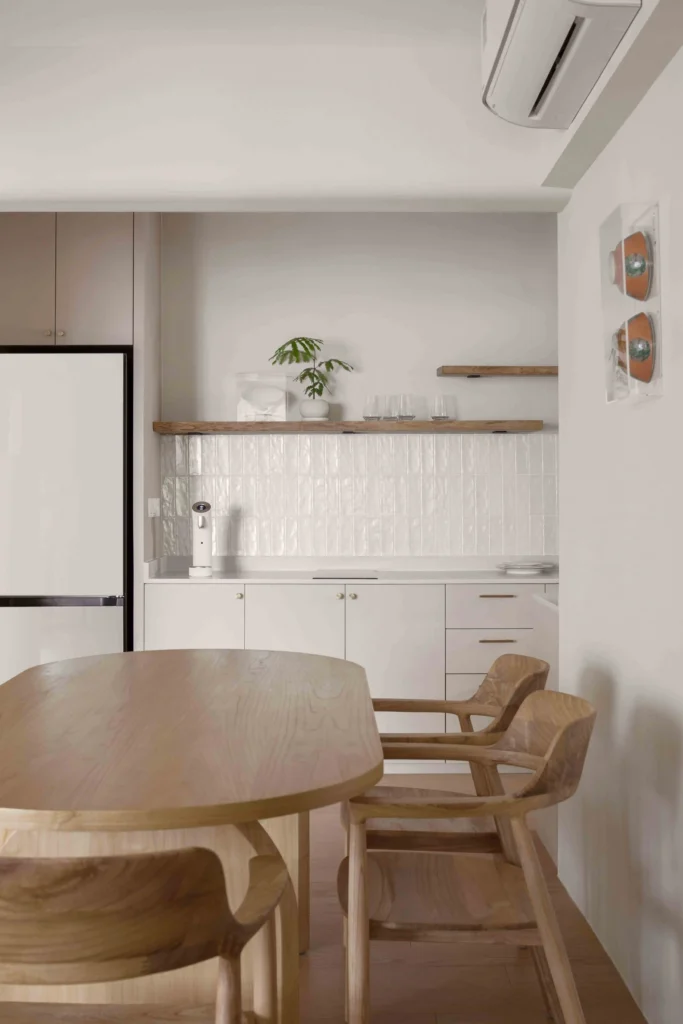 Minimalist Scandinavian kitchen with white tiled backsplash, open wood shelves and a light-wood dining set.