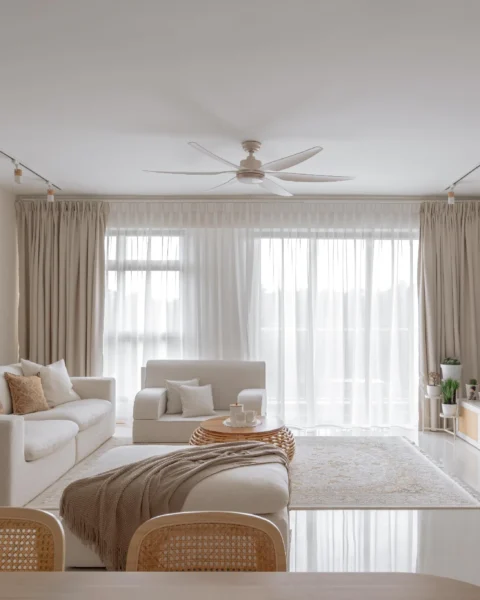 Bright neutral living room with sheer curtains, a rattan-front TV console, and soft furnishings in beige tones.