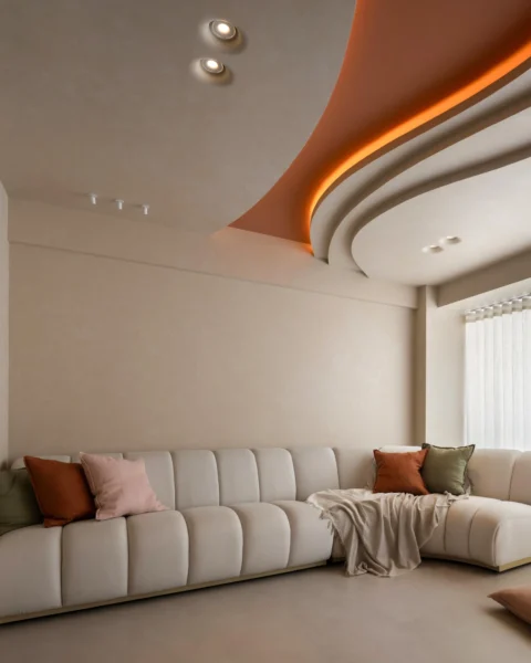 Cream sectional sofa beneath a curved ceiling with cove lighting, styled with warm-toned accent cushions.