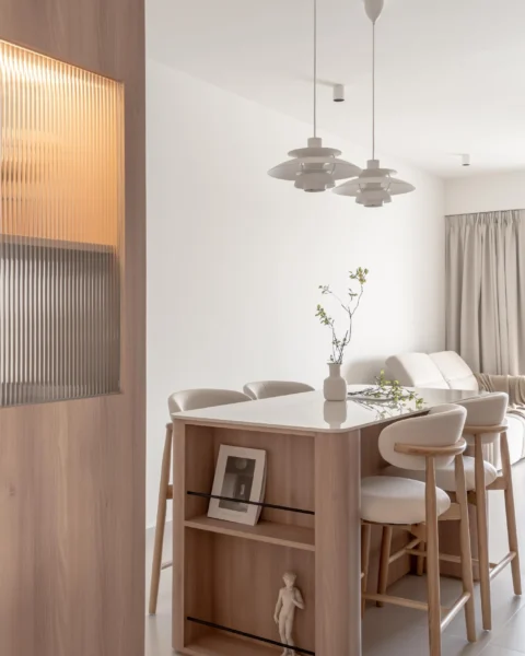 Scandi-style dining and kitchen area with a pale wood island, pendant lights, and a ribbed glass cabinet feature.