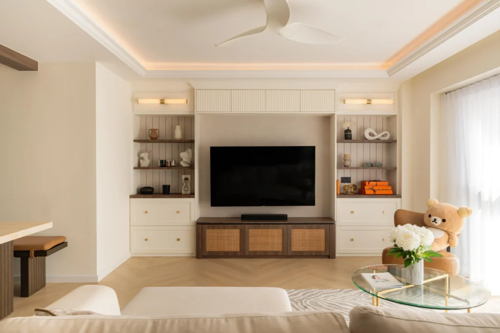 British colonial-style TV feature wall with moulding, cane-front cabinetry, warm lighting, and herringbone timber flooring.