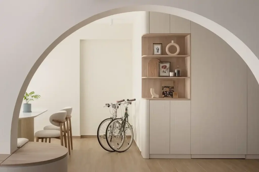 Curved archway framing a built-in bench and light oak shelving in a warm neutral dining nook.