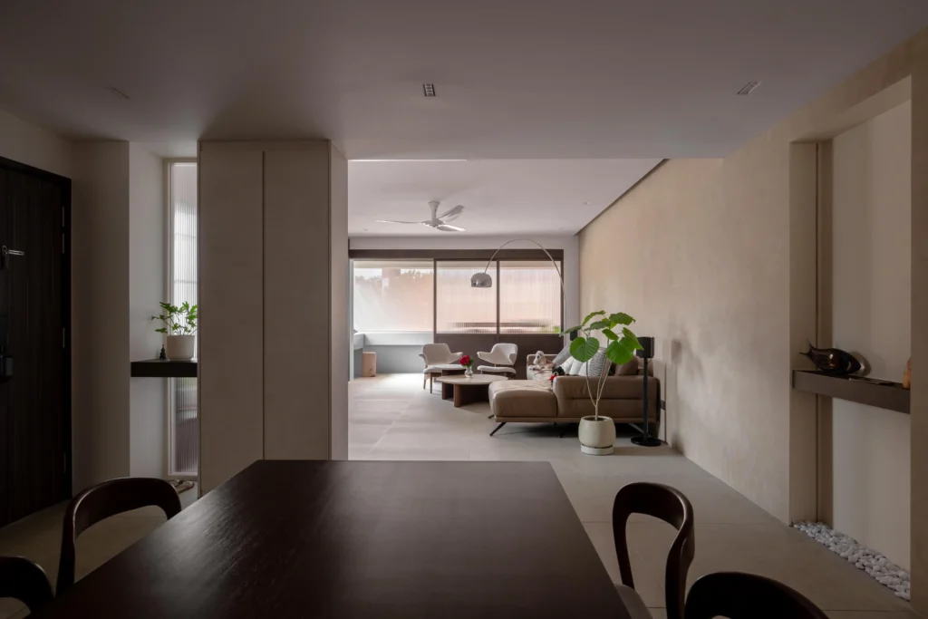 Earth-toned open-plan living and dining area with plaster-textured walls, low seating, and soft natural light.