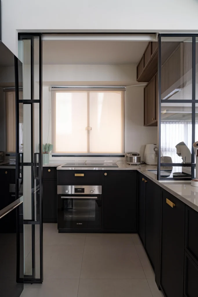 Compact black-and-white kitchen with brass handles and a black-framed sliding glass door.