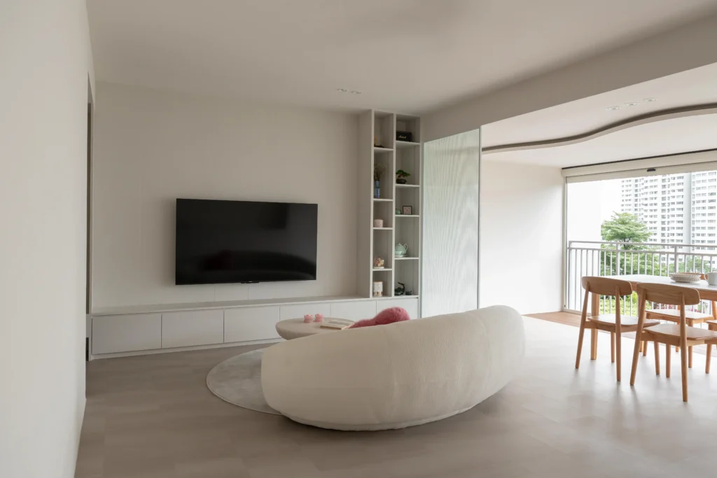Neutral open-plan living and dining area with a curved sofa and sliding doors leading to a balcony.
