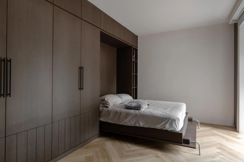 Bedroom with wall-to-wall timber cabinetry and a fold-down Murphy bed.