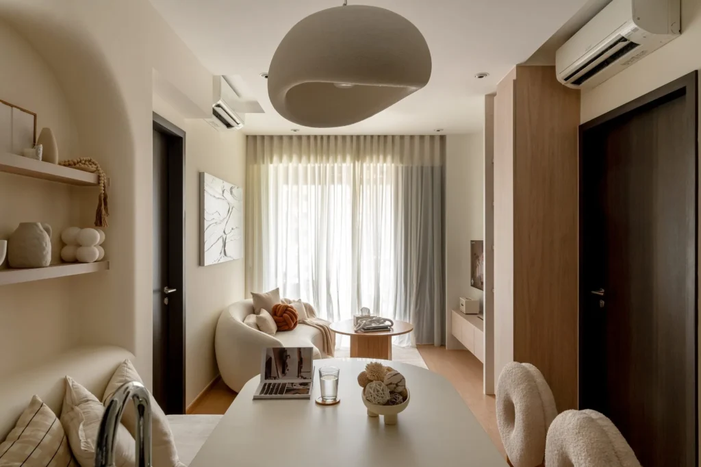 Compact living room with a curved sofa, round coffee table, and full-height curtains by the window.