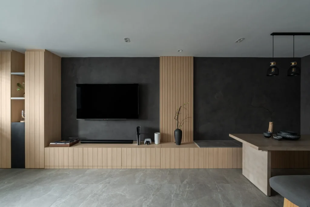 Open-plan living room with a wall-mounted TV on a light wood panel and a ceiling fan.