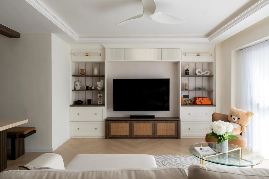 Living room with built-in shelving, a TV console, and rattan-front cabinets.