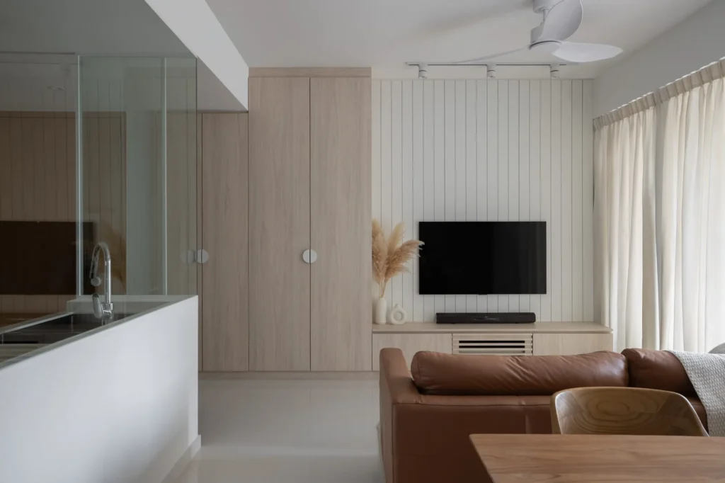 Living room with a wall-mounted TV, vertical wall panels, and built-in storage cabinetry.