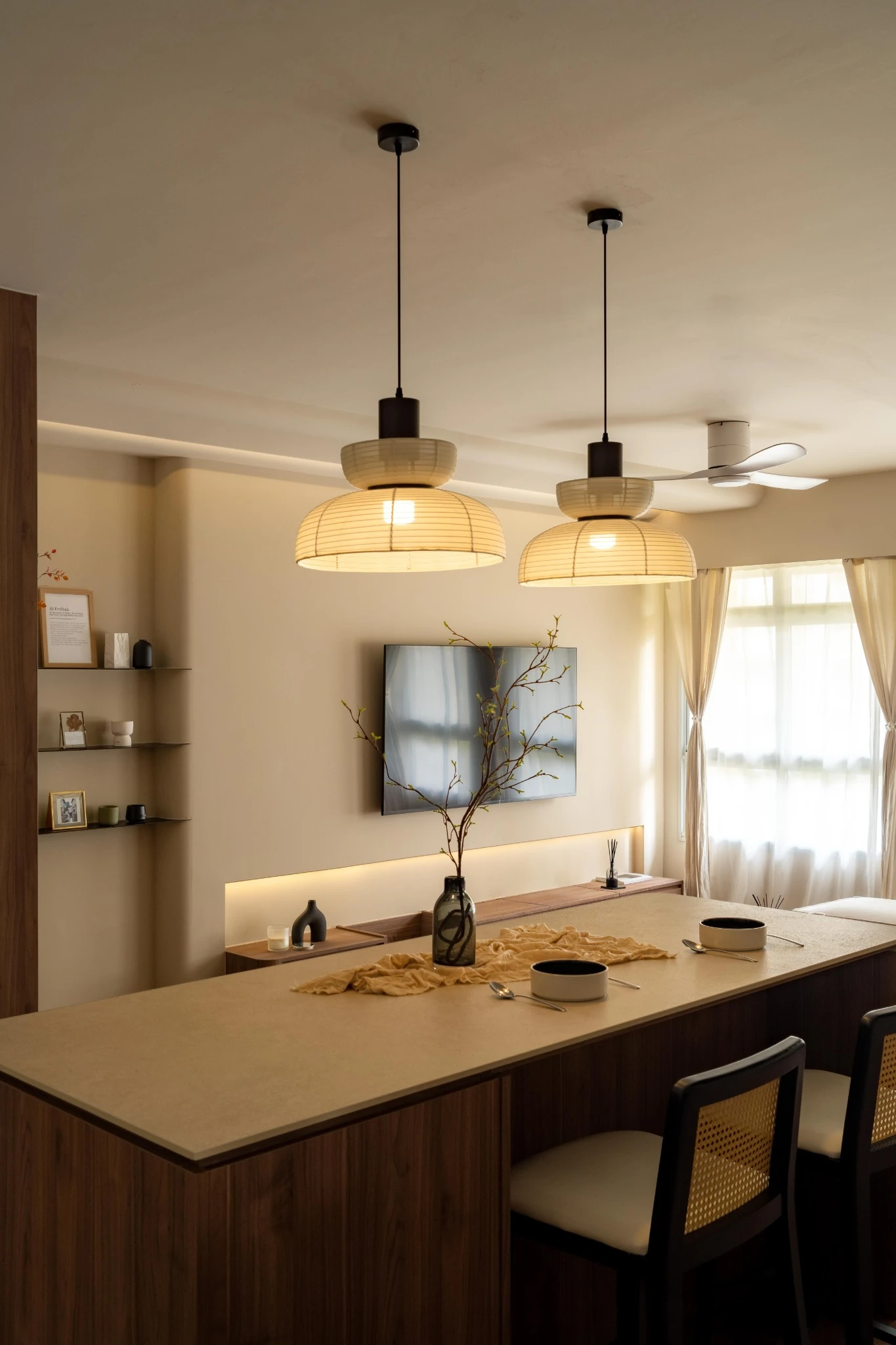 Warm-toned kitchen island with wood cabinetry, soft pendant lights, and a cosy dining setup by the window.