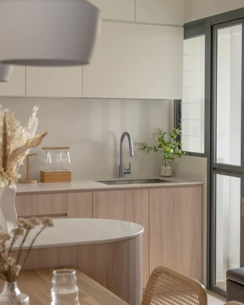Modern Japandi interior design featuring light wood kitchen cabinets, a curved island, and minimalist decor under soft warm lighting.